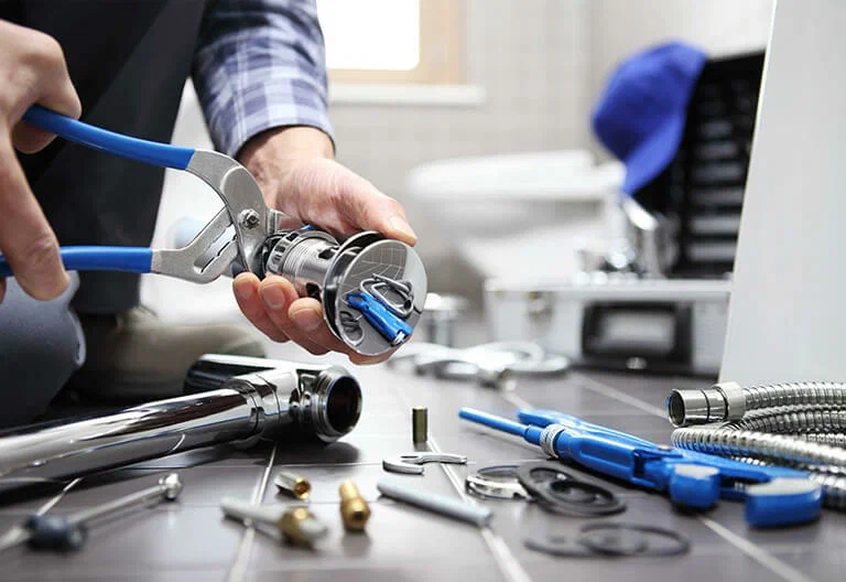 Technician repairing a plumbing fixture with professional tools in Evans
