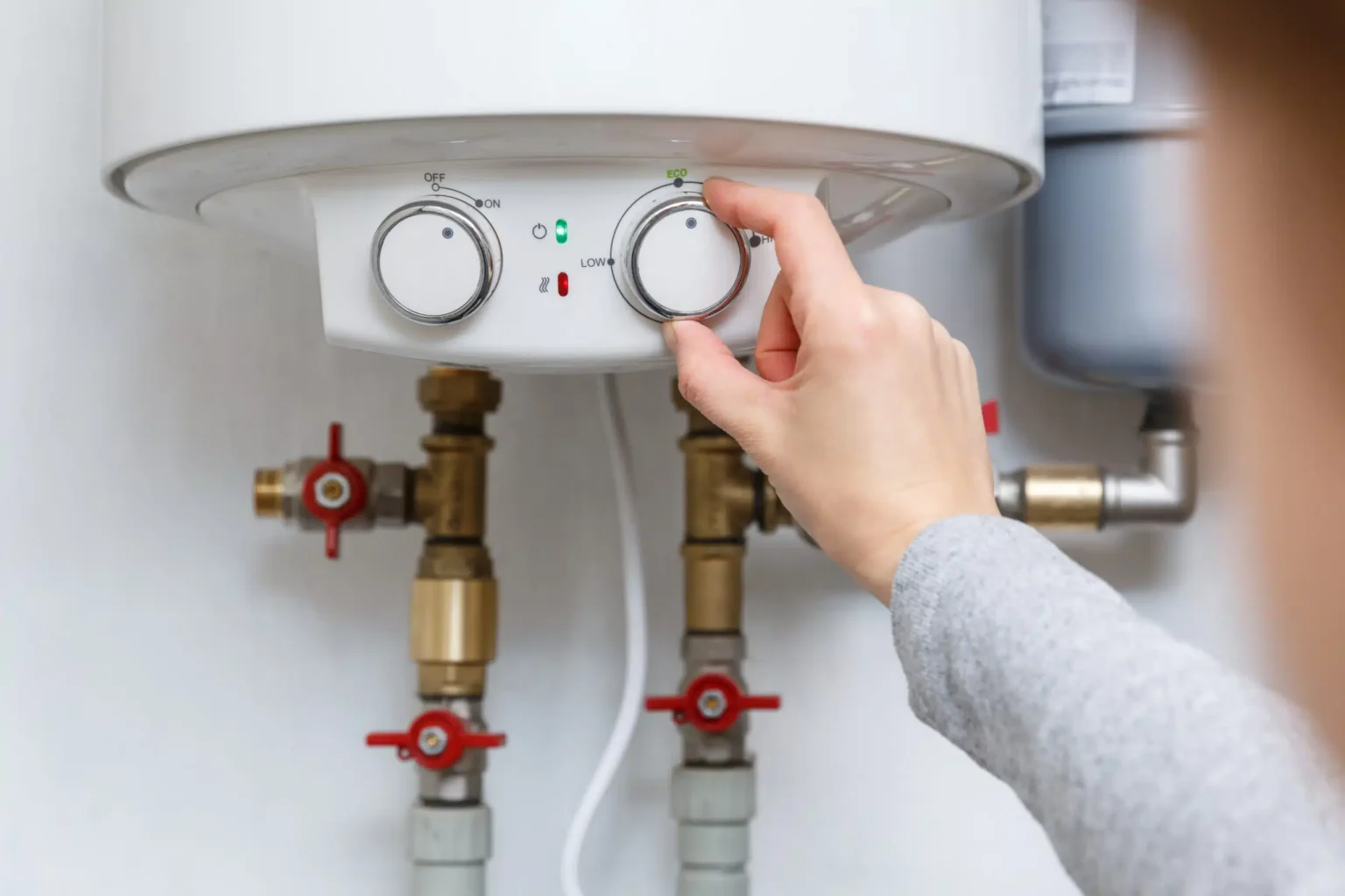 Homeowner adjusting the temperature controls on a water heater in Evans