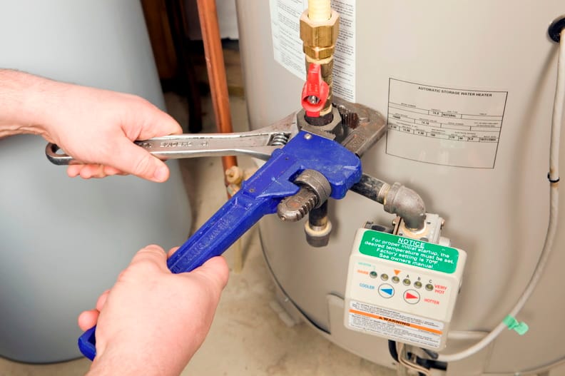 Plumber repairing a water heater valve in Evans